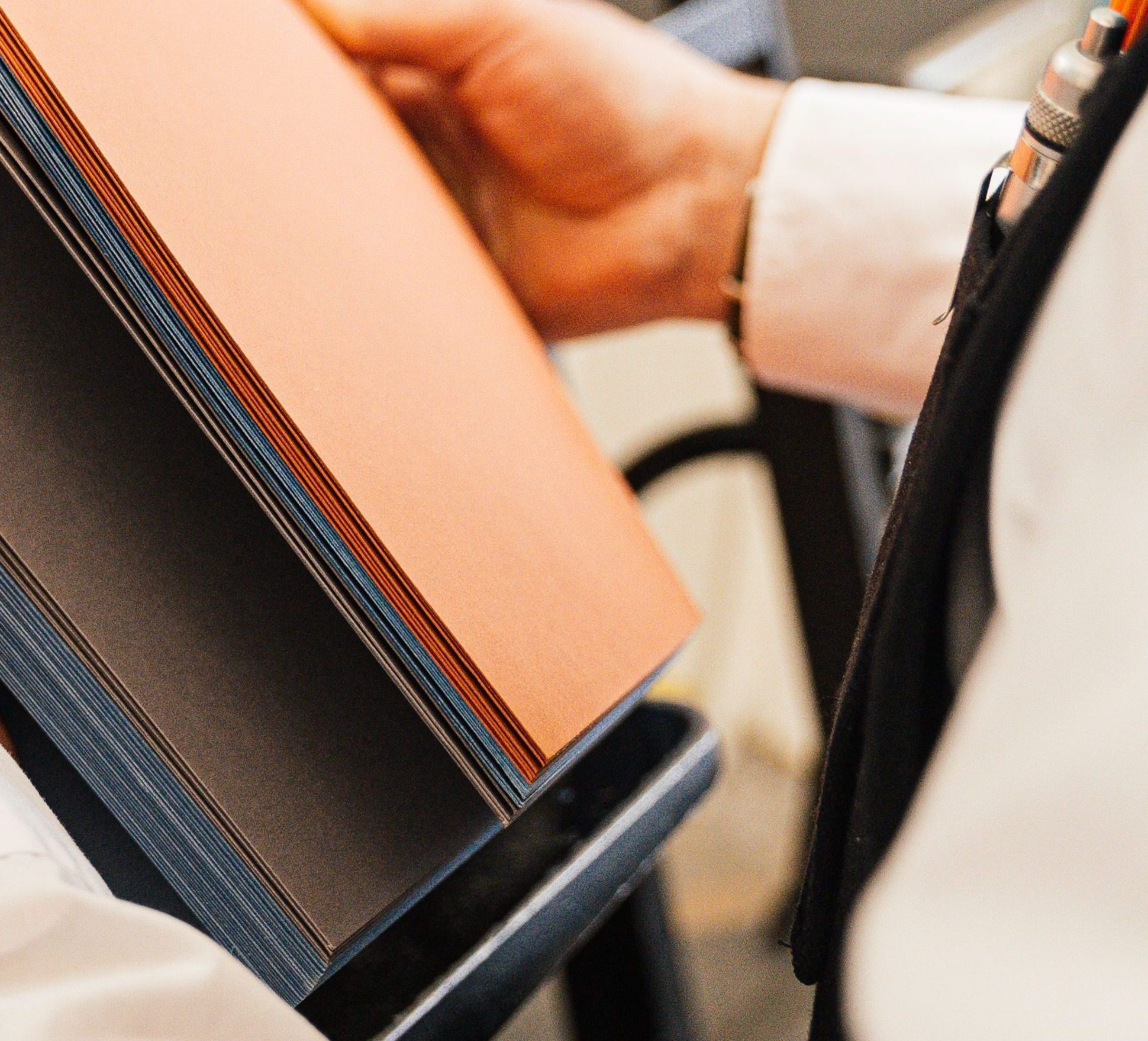 Person holding papers near a printing press in a workshop setting.